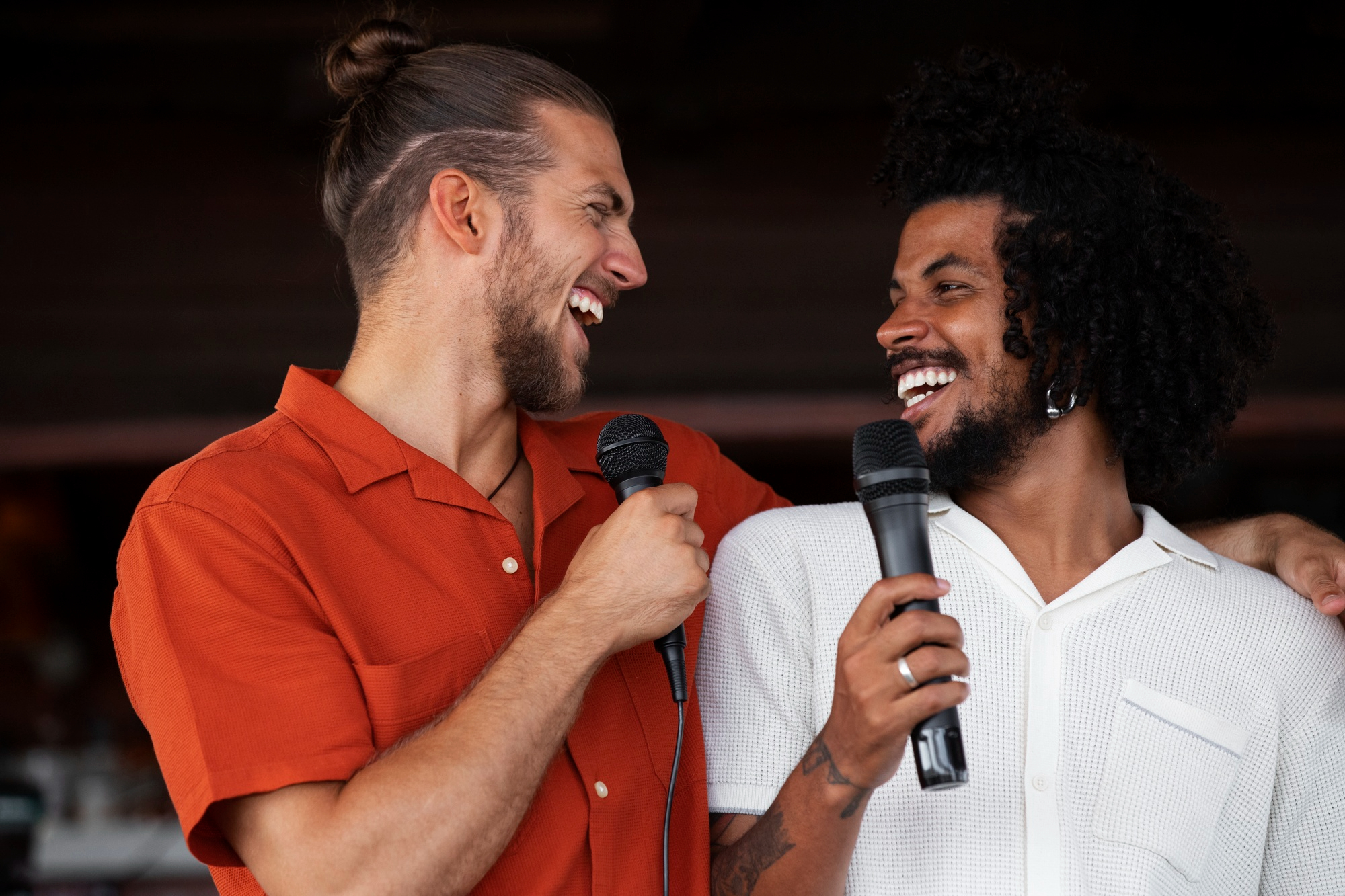 Two singers smiling and sharing a microphone, the spirit of joyful connection through music.